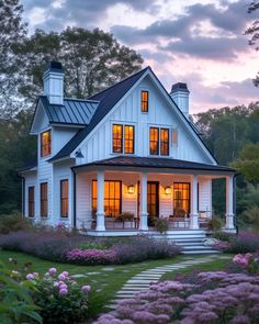 a white house with lots of windows and flowers in the front yard at night time