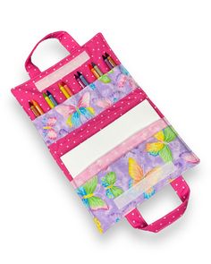 a pink and purple bag with markers, pens and pencils in it on a white background