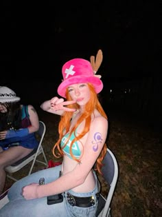 a woman with red hair wearing a pink hat and sitting on a chair in the grass