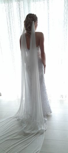 a woman in a white wedding dress is looking down at the floor with her veil draped over her head