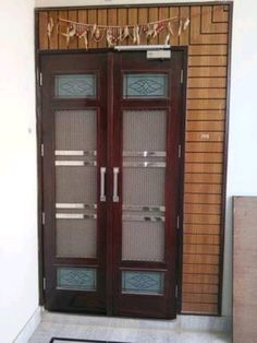 two brown double doors in front of a wall