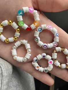 a person is holding five different bracelets in their hand, all with smiley faces on them