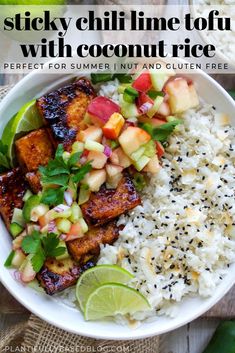 a white bowl filled with rice and fruit next to sliced limes on the side