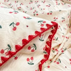 an unmade bed with cherries and ruffles on the sheets is shown