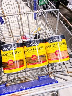 three cans of minwax wood finish sitting in a shopping cart