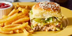 a hamburger with lettuce and cheese next to french fries on a yellow plate