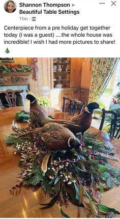 two pheasants sitting on top of a table surrounded by christmas greenery