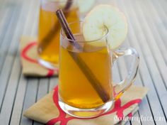 two mugs filled with apple cider and cinnamon sticks