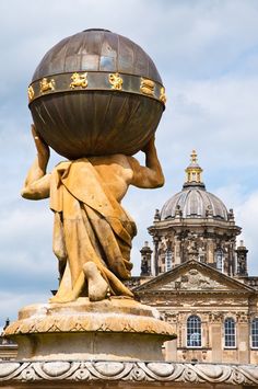 a statue with a large globe on it's head in front of a building