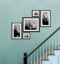 black and white photo frames hanging on the wall next to a stair case in a home