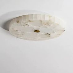 a close up of a light fixture on a white wall with a gold button in the middle