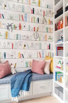 a room with bookshelves and colorful wallpaper on the walls, along with two benches