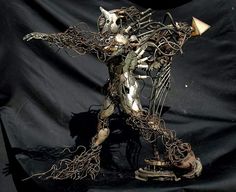 a sculpture of a cat made out of wire and metal parts on a black background