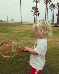 a young child holding a tennis racket and ball