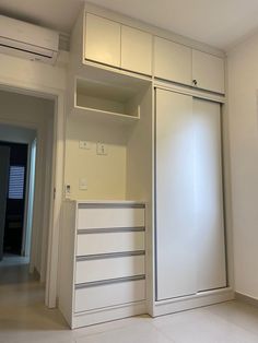 an empty room with white cupboards and drawers on the wall next to a door