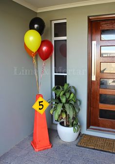 a number five sign and some balloons in front of a door with a potted plant