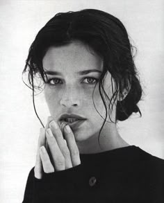 a black and white photo of a woman with her hand on her chin looking at the camera