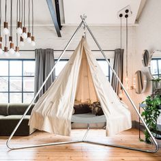 a teepee tent in the middle of a living room with wooden floors and windows