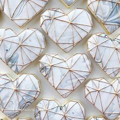 many heart shaped cookies are decorated with white and blue icing, some have gold lines