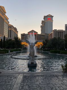 a fountain in the middle of a plaza with buildings in the backgrouds