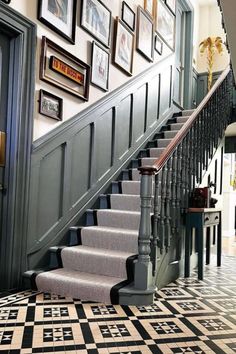 a staircase with pictures on the wall and carpeted stairs leading up to an entrance