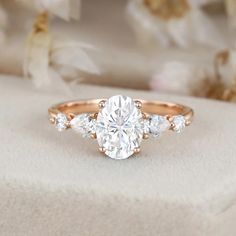 an oval cut diamond ring with three side stones on the band, set in 18k rose gold