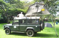 a man is sitting on top of an army green truck with a tarp over it