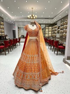 Bridal Lehenga BL-004 is a stunning lehenga for brides. It is adorned with intricate details and made from quality fabric for a luxurious feel. The lehenga is stylish and comfortable, perfect for a memorable wedding day. Fabric: Raw Silk WASH CARE INSTRUCTIONS - Please Dry clean only when it is applicable Ready to Ship! Orange Wedding Lehenga Indian Bridal, Lenga Design Indian Weddings, Wedding Lehenga In Dola Silk With Zari Work, Dola Silk Lehenga With Cutdana For Wedding, Unstitched Lehenga With Traditional Drape For Wedding, Floor-length Lehenga With Dupatta For Wedding, Intricate Embroidery Fitted Lehenga For Wedding, Luxury Traditional Orange Lehenga, Rustic Orange Bridal Lehenga