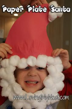 a young child wearing a paper plate santa hat