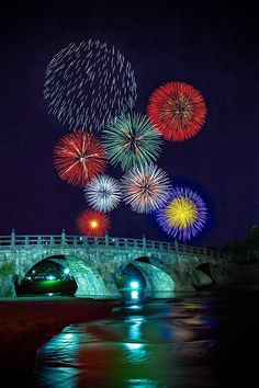 fireworks are lit up in the night sky above a bridge