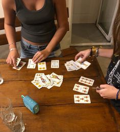 two women playing cards on a wooden table