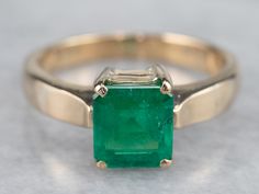 The mounting of this ring is vintage, crafted of a perfect, 18 karat yellow gold. We've set it with a gorgeous emerald that looks amazing surrounded by the bright polish of the prongs! Shades of green simply gleam from this gorgeous ring!Metal: 18K Yellow Gold Gem: Emerald 1.295 CaratsGem Measurements: 6.9 x 6.3 mm, Emerald Cut Ring Size: 6.50Marks: “18K” Stamped on the inside band Timeless Green Emerald Ring Stamped 14k, Timeless 14k Stamped Green Emerald Ring, Classic Emerald Ring Stamped 14k, 14k Gold Emerald Ring Square Cut, Classic 14k Stamped Emerald Cut Emerald Ring, Classic Solitaire Emerald Ring For May Birthstone, Classic Green Emerald Ring With Prong Setting, Square Cut Emerald Ring In 14k Yellow Gold, Heirloom Green Emerald Solitaire Ring