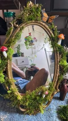 a mirror that is sitting on the ground in front of a table with plants and mushrooms