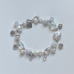 A sweet handmade bracelet ✿ Made with freshwater pearls, glass crystal beads, metal accents, and natural stone ✿ Pearlescent white, iridescent clear, marbled white, milky white, and silver ✿ Toggle Clasp. Some beads may be added or removed depending on the length selected White Beaded Pearl Charm Bracelet, White Pearl Beaded Charm Bracelet, Adjustable White Charm Bracelet With Pearl, Handmade White Pearl Charm Bracelet, White Pearl Charm Bracelets For Jewelry Making, White Pearl Charm Bracelet, White Beaded Crystal Pearl Bracelet, Adjustable White Crystal Pearl Bracelet, Handmade White Pearl Crystal Bracelet