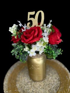 a gold vase filled with red roses and white flowers on top of a golden plate