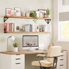 a desk with a computer, books and plants on the top shelf in front of it