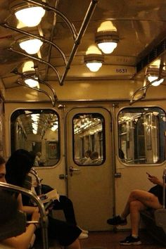 people are sitting on the subway train and looking at their cell phones as they read