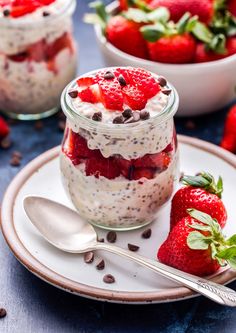 two jars filled with chia pudding and strawberries on a plate next to spoons