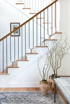 two vases on the floor next to a stair case with branches in front of it