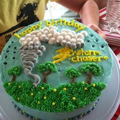 a birthday cake with green frosting and trees on it is being held by a person