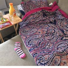 a bed with two pillows and some socks on the floor next to it in front of a coffee table