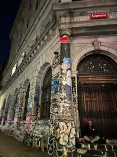 an old building with graffiti all over it's walls and door is lit up at night