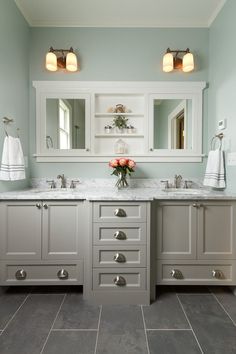 a bathroom with two sinks and white cabinets