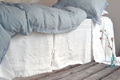 a bed with blue and white pillows on top of it next to a wooden table