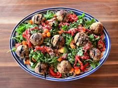 a salad with mushrooms and tomatoes in a blue bowl on a wooden table top, ready to be eaten