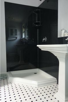 a black and white bathroom with a pedestal sink, shower stall and standup shower