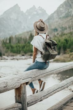 a woman sitting on a wooden bridge with a backpack