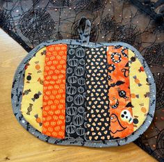 an orange and black patchwork purse sitting on top of a wooden table next to halloween decorations