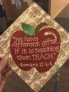 someone is holding up a graduation cap with an apple on it