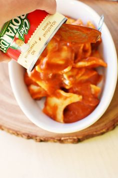 a person is dipping sauce on some food in a white bowl with tortilla chips